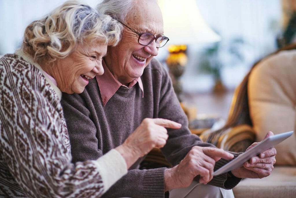An older couple smiling at a tablet together